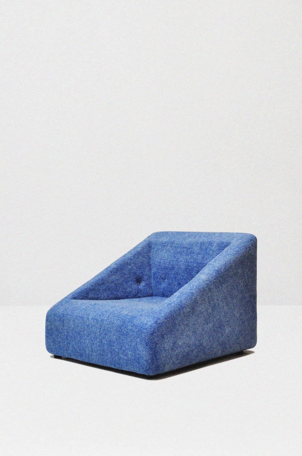 Armchair upholstered in blue mélange ādara® Felt, photographed in a studio