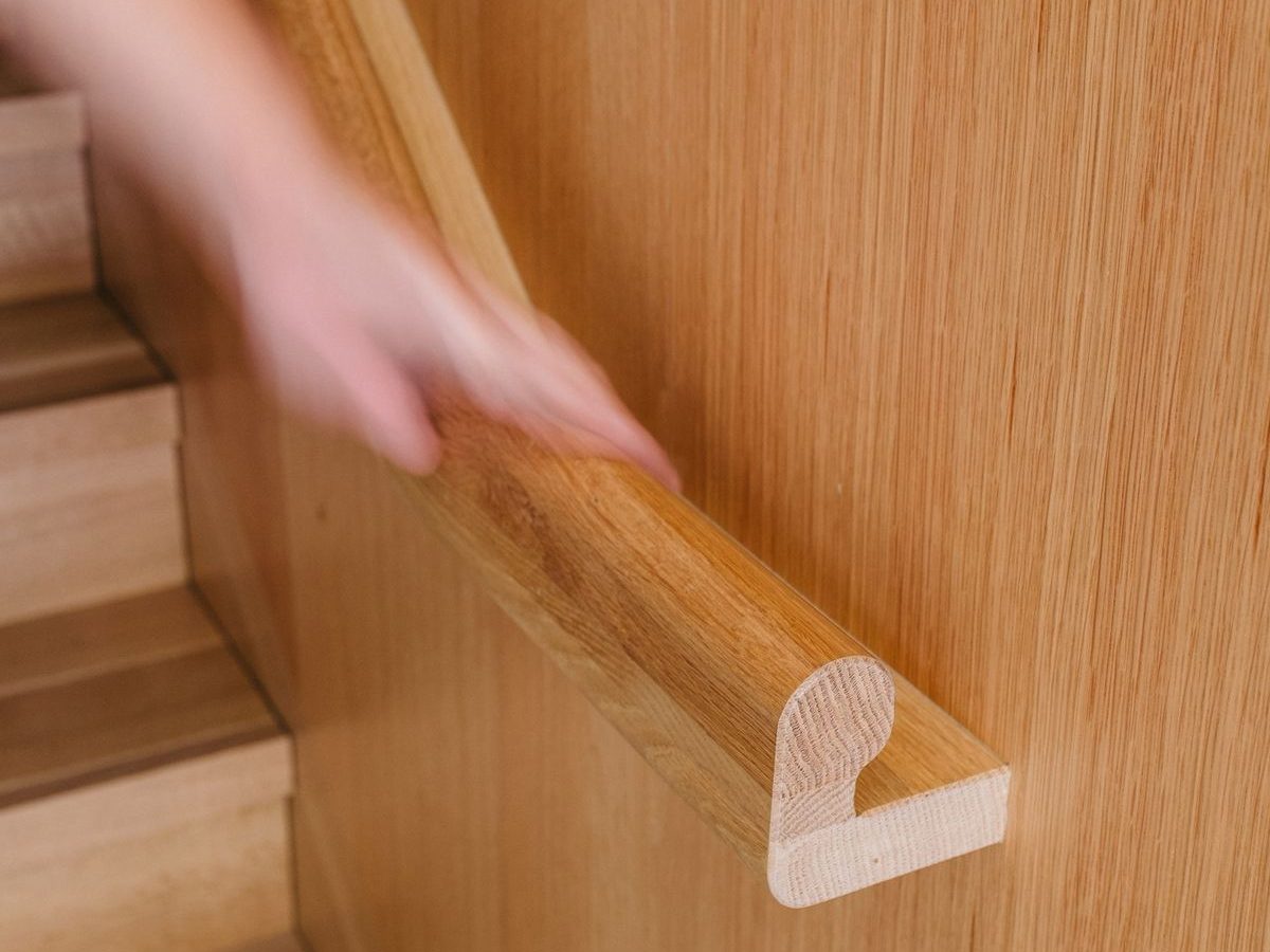 A hand moving along a shaped wooden handrail